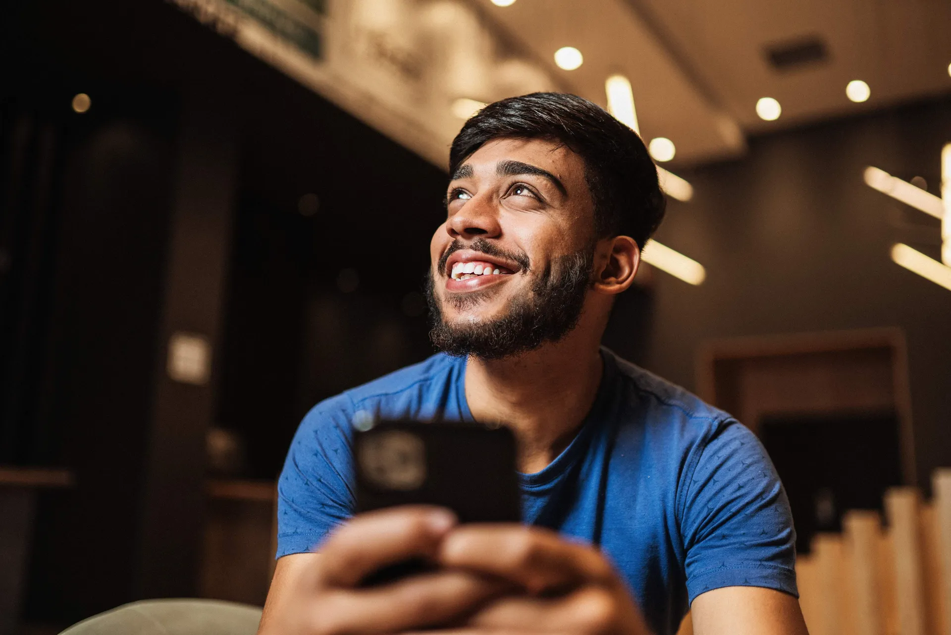 Pessoa sorrindo ao conferir a confirmação de uma cobrança no smartphone